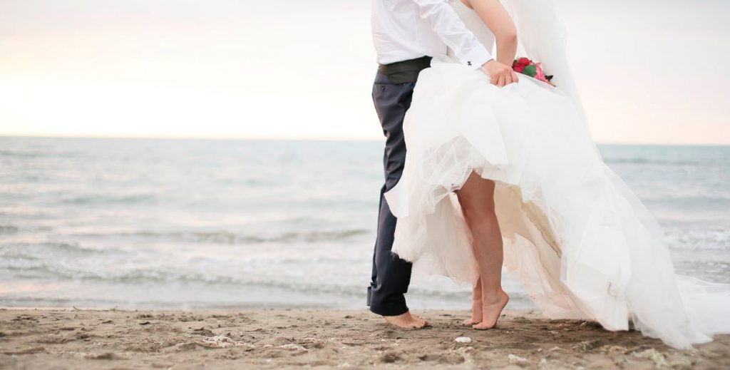 alt="Novios celebrando boda en la playa" />